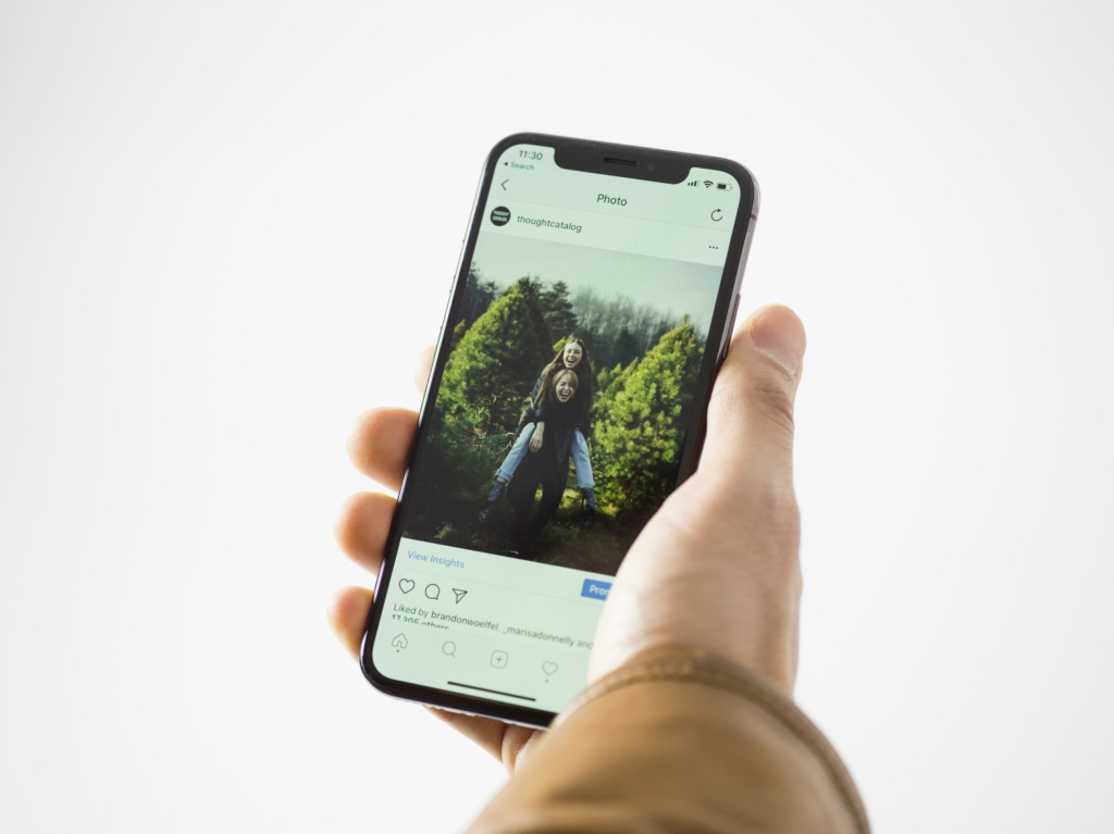 A close up shot of a hand holding a smart phone displaying a post on Instagram