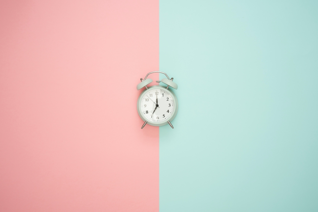 Silver bell alarm clock across a striking two color background | Imagely An alarm clock